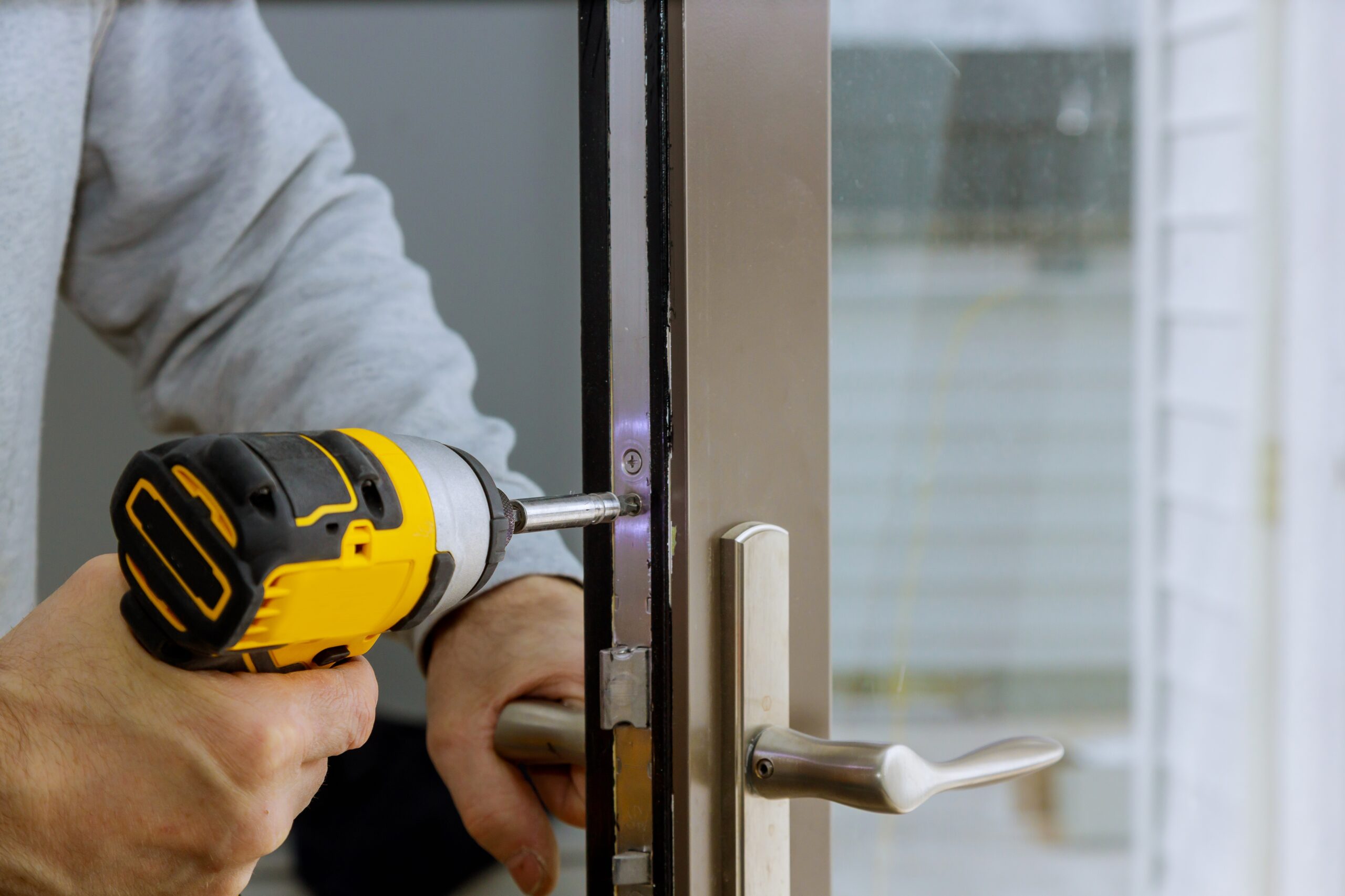 Locksmith hand holds the screwdriver in installing new house door lock