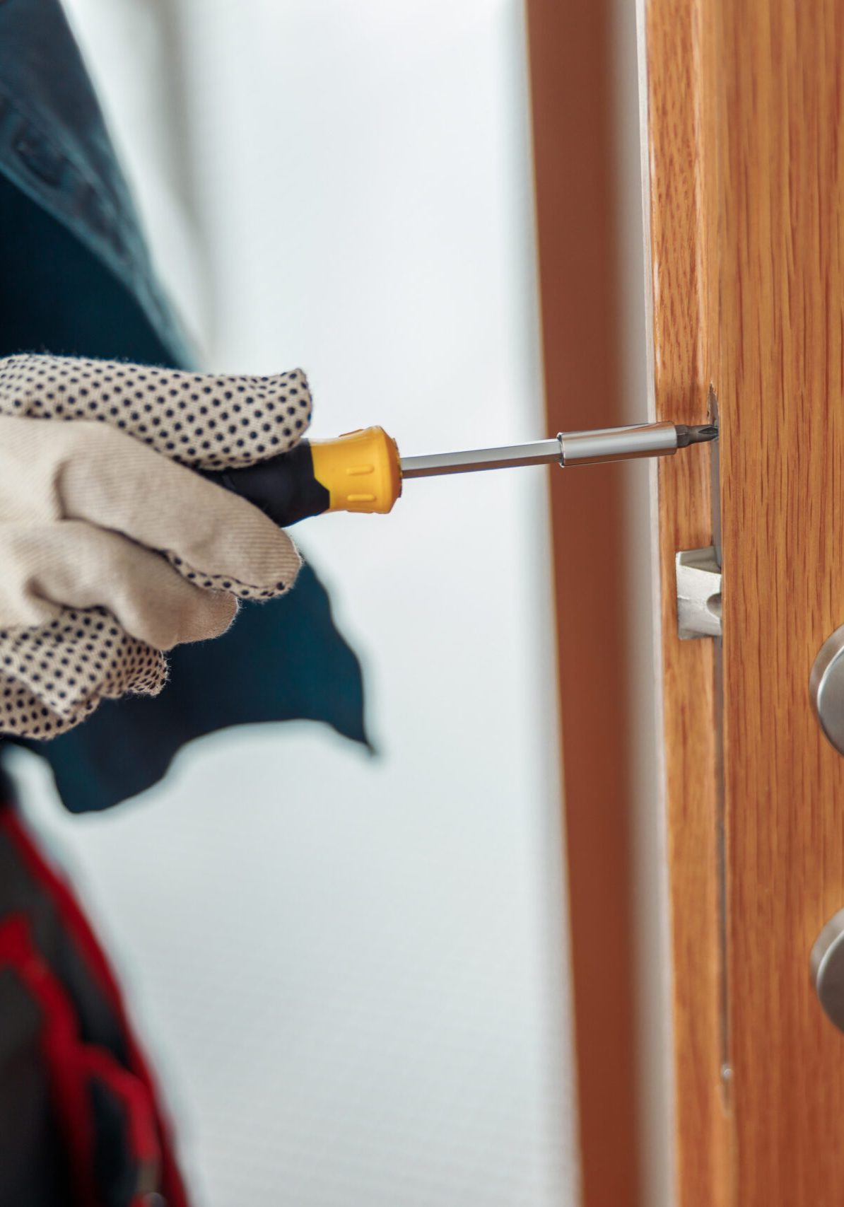 Locksmith workman in uniform installing door knob. Professional repair service. Maintenance Concept